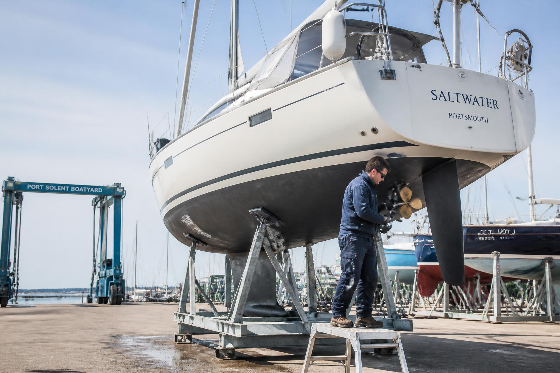 Marine engineer working on the saildrive of a yacht hauled out on stands in a boatyard